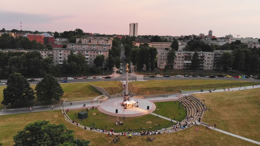 Aerial view St. Johns midsummer festival concert in city Siauliai with people sitting in park listening live music. Lithuania festival and holiday events concept.