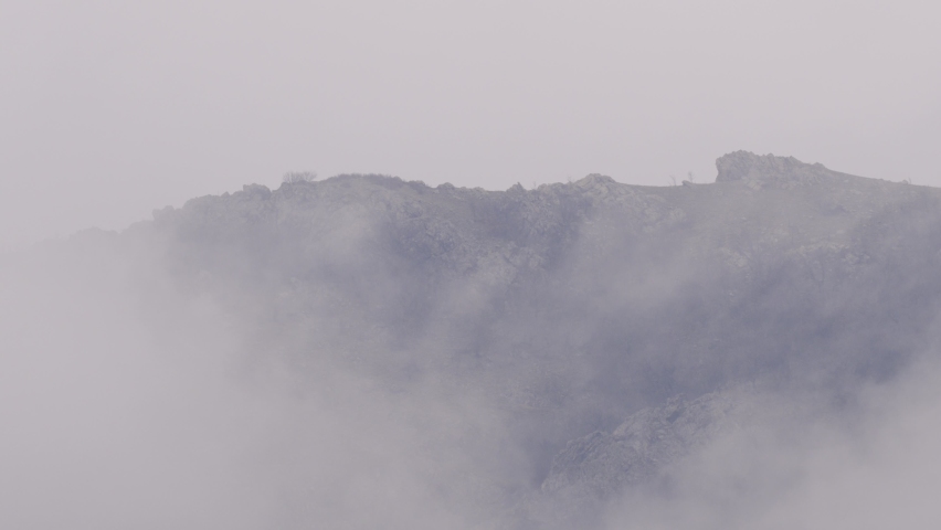 Wonderful alpine scenery with great rocks and mountains in dense low clouds