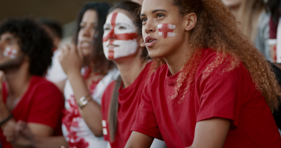 Female soccer fans of England watching and starts celebrating after their team's victory. English female spectators enjoying after a win at stadium.
 Royalty-Free Stock Footage #1074811778