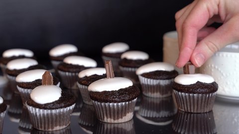 4K clip of woman's hand decorating mini smores cupcakes with chocolate and graham cracker pieces, cupcake reflections can be seen. Baking, series.