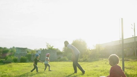 summer, vacation, nature, happy family, childhood, paternity, father Day - Dad with small preschool children baby kids run playing catches catch-up have fun with big inflatable ball in park at sunset