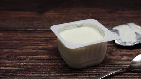 Children's Cottage Cheese In Plastic Containers On A Wooden Table With Spoon. Panning Slider Shot.