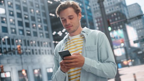 Portrait of a Handsome Young Man Wearing Casual Clothes and Using Smartphone on the Urban Street. Stylish Male in Big City Connecting with People Online, Messaging and Browsing Internet.
