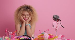 Displeased curly haired woman looks sad overviews different cosmetic products going to record video make up at home feels unhappy because of failure cannot become famous blogger after various attempts