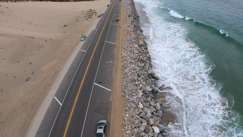 Pacific Ocean Waves Crashing on California Shore, Aerial Drone Shot Over Moving Traffic