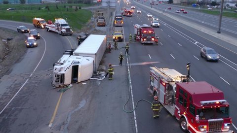 Brampton , Canada - 04 19 2021: Firefighters spreading absorbent at a truck accident. Truck accident on a busy highway.