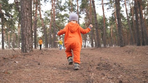 baby run. little boy in orange jumpsuit a walk through the forest park. kid dream happy family concept. baby run in the park. fun happy childhood carefree family walk child in the park