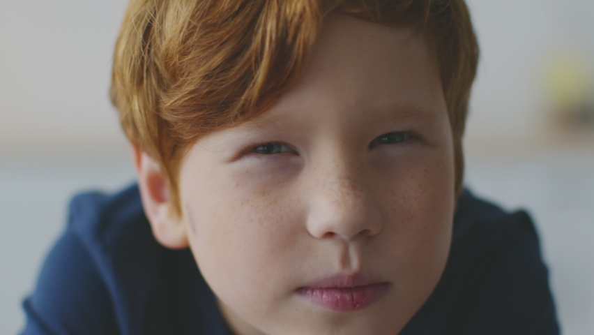 Kids eyesight problems. Close up portrait of little redhead boy with freckles squinting his eyes, peering to camera, feeling troubles with vision, reading difficulties concept, slow motion Royalty-Free Stock Footage #1074844124