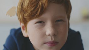 Kids eyesight problems. Close up portrait of little redhead boy with freckles squinting his eyes, peering to camera, feeling troubles with vision, reading difficulties concept, slow motion - Powered by Shutterstock - Get 15% off with code: PIKWIZARD15