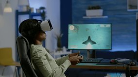 Black woman gamer playing video game at powerful computer late night wearing vr headset. Excited player using wireless controller for virtual tournament gaming space shooter at home