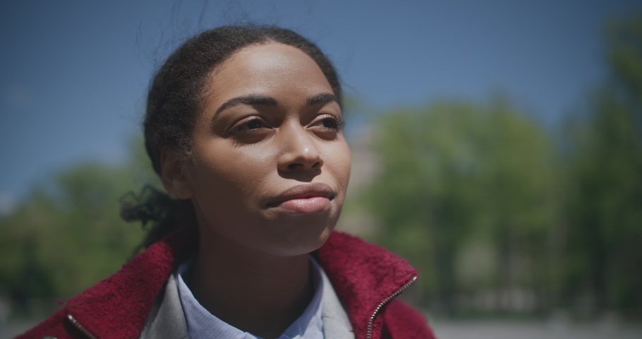 Enjoying summer day. Close up portrait of young peaceful african american woman standing outdoors in park and breathing, tracking shot, slow motion