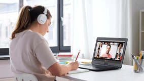 education, online school and distant learning concept - student woman in headphones with laptop computer having video conference at home
