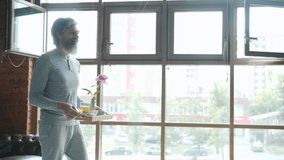 Slow motion of caring man bringing breakfast to bed to cheerful woman kissing expressing love while wife is smiling and smelling flower. Family and relationship concept. - Powered by Shutterstock - Get 15% off with code: PIKWIZARD15