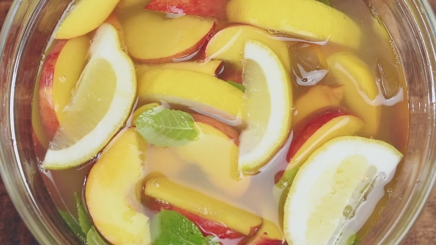 Preparation iced fruit green tea in a glass bowl. Adding cold water to the mixture.