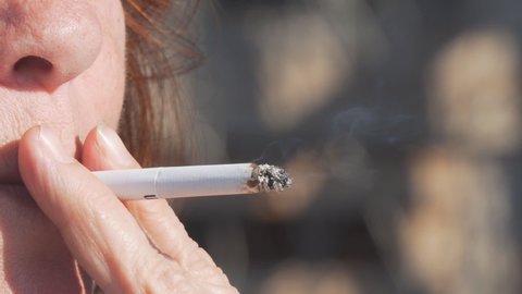 A woman smokes in close-up. Cigarette in the woman's hand