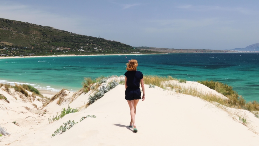 Woman walking in the white sand dunes across Tarifa beaches
