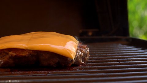 Mouth-watering cheeseburger cutlet is frying on the grill with cheese on the top