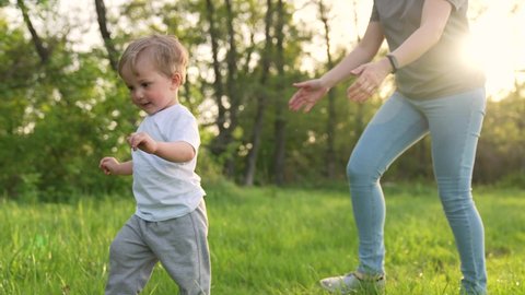 Happy kid run in park. Mom and baby play outdoors. Happy family concept. Smile of a baby. Kid play in park. Happy family in park. Kid smile and run. Baby dream. Mom and baby family games.