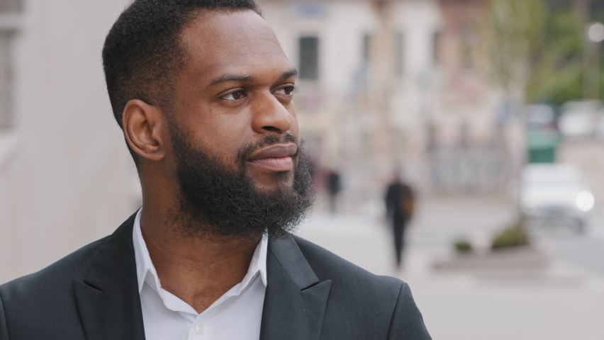 Headshot smiling bearded millennial African businessman looks at camera. Ambitious corporate staff member in formal suit pose outdoors. Career growth, hired employee, company founder portrait concept Royalty-Free Stock Footage #1074879281