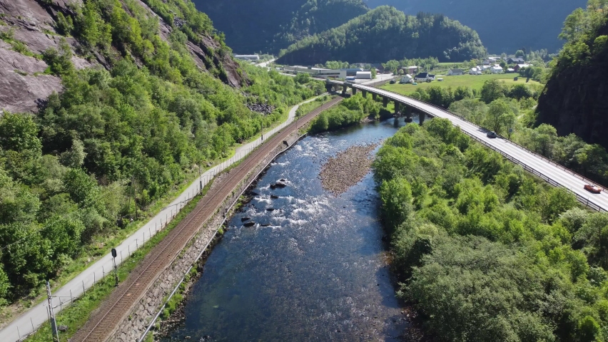 Road E16 crossing concrete bridge over Dalekvam river between Bergen and Voss - Railroad between Bergen and Oslo on left side - Aerial Norway