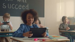 Smiling african american girl using digital tablet in school class with classmates. Afro schoolgirl doing online class work on tablet computer. Mixed race students learning online with pads at school - Powered by Shutterstock - Get 15% off with code: PIKWIZARD15