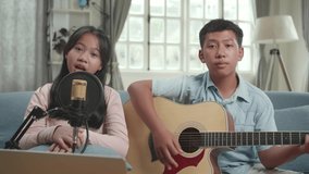 Asian Boy Playing Guitar And Girl Sing A Song At Home. Children Is Broadcasting Live On The Internet
