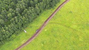 Aerial video of off-road car driving on a country dirt road. Siberia, Russia