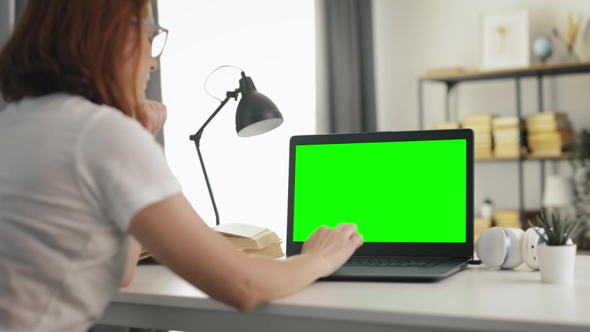 Side view of mature woman using wireless laptop with chroma key screen while sitting at white table. Female working on portable computer from home. Royalty-Free Stock Footage #1074907181