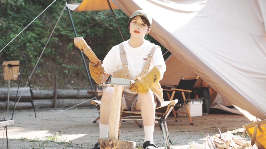 Solo camp image - Young woman chopping firewood