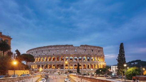 Rome, Italy. Colosseum. Traffic Near Flavian Amphitheatre During Sunset, Evening And Night Time. Famous World Landmark UNESCO. Day To Night Time Lapse.