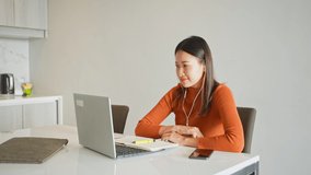 Asian Businesswoman online meeting with business partnership on laptop computer at home. Young woman working online corporate business job at apartment. Modern life and remote working concept.