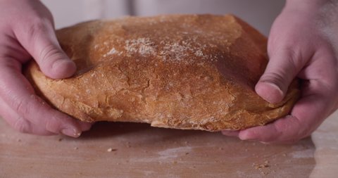 Close up of baker hands breaking homemade bread
