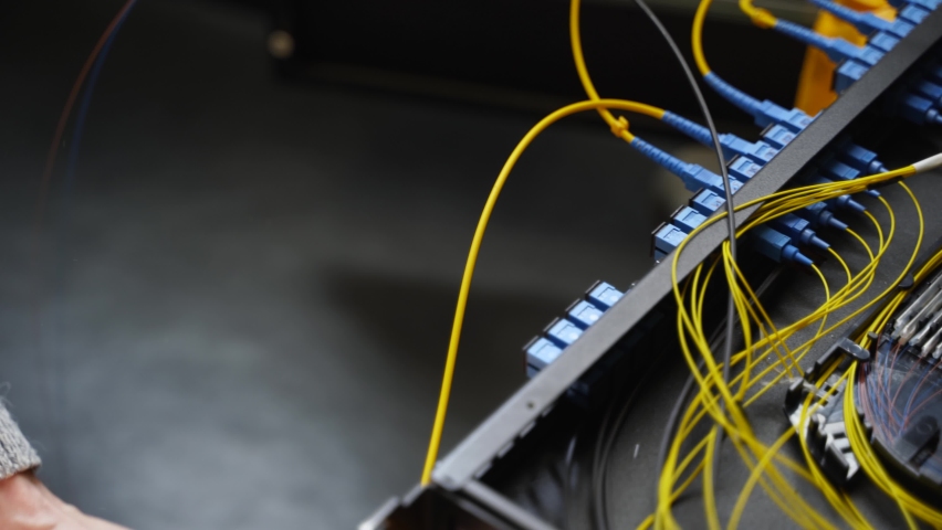 Worker connects optical line internet wire in connection box. Service man soldering optical fiber. Internet service provider engineer working in server room with the optic fiber and router wiring. Royalty-Free Stock Footage #1074934613