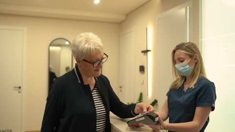 Senior woman paying with credit card at dentist reception