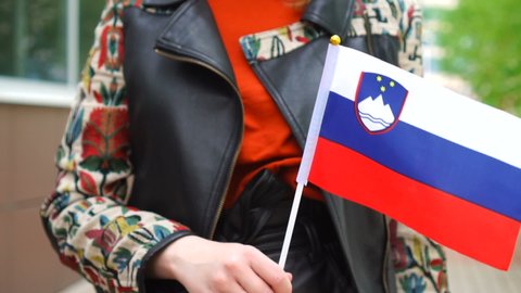 Unrecognizable woman holding Slovene flag. Girl walking down street with national flag of Slovenia