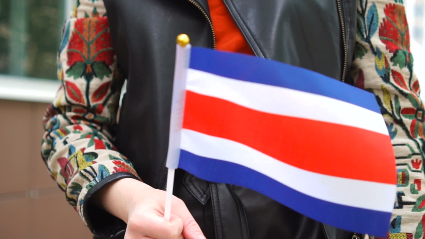 Unrecognizable woman holding Costa Rican flag. Girl walking down street with national flag of Costa Rica Royalty-Free Stock Footage #1074938867