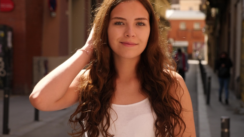 Portrait of positive confident girl, standing in good weather on the street. High quality 4k footage