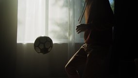 Man minting a soccer ball, professional football player training in the living room at home or office, doing sport during coronavirus covid 19 lockdown. - Powered by Shutterstock - Get 15% off with code: PIKWIZARD15