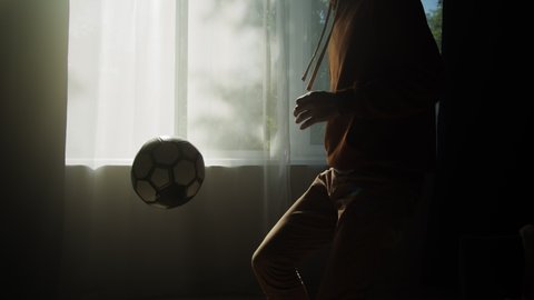 Man minting a soccer ball, professional football player training in the living room at home or office, doing sport during coronavirus covid 19 lockdown. Stockvideó