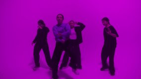 Professional choreographer dancing with backup dance on color changing neon background in studio for dance video clip. Four women dancers showing hip hop movements. Advertising of dance school.