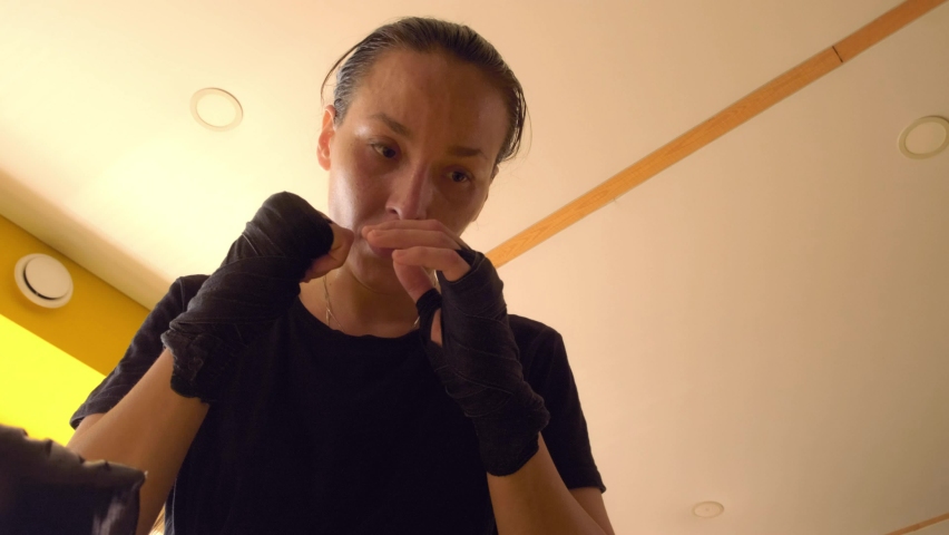 A beautiful Asian woman strongly beats her hands on a wrestling dummy from above. Mixed fight, MMA