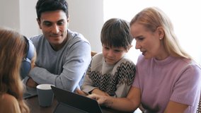 Caucasian handsome man with woman and showing video to son in laptop with teenage girl with headphones using digital tablet and pen doodling on screen