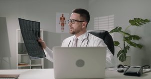 Doctor talking to a patient via internet. Professional healthcare service worker consulting the patient remotely, checking x-ray images 4k footage
