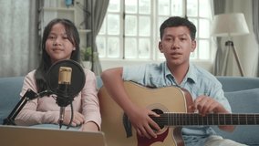 Asian Boy With Guitar And Girl Talking To Camera. The Children Is Broadcasting Live On The Internet
