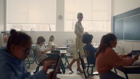 Female teacher and students with digital tablets having lesson in classroom. Focused kids learning at school with modern gadgets. Cheerful schoolteacher teaching students in elementary school - Powered by Shutterstock - Get 15% off with code: PIKWIZARD15