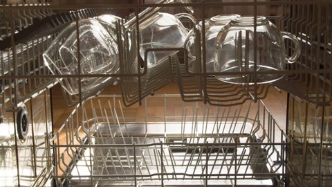 Loading the Dishwasher with Plates. The view from the inside of the dishwasher. The cymbals appear in the basket in a stop motion style. The door closes