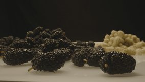 Group of fresh , organic , black and white mulberry fruits on the table .  Close up view of differnt kind of mulberries . Video Shot on ARRI ALEXA Cinema Camera with Laowa lens in slow motion . 