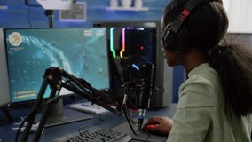 Pro cyber black woman streaming videogame, reading on stream chat and playing space shooter on RGB powerful computer. Streamer sitting on gaming chair playing game during online esports tournament.