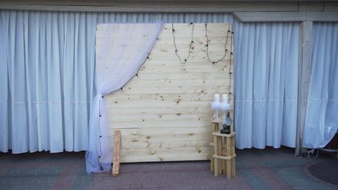 Photo area for celebration. Wedding vintage photo area with wooden background, candles, kerosene lamp, chiffon fabric and a garland of light bulbs.