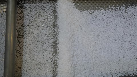 Recycled plastic granules - polyethylene or propylene pellets on shale shaker, conveyor belt of waste plastic recycling machine - top view. Separation, ecology, automated technology concept